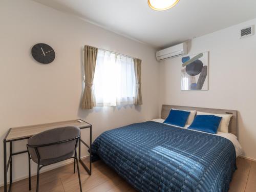 a bedroom with a bed and a desk and a clock at 新築貸し切り宿 Karatsu House A in Karatsu