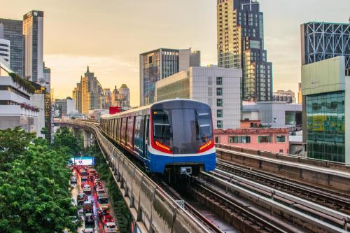 a train on a track in a city with buildings at Crowne Plaza Bangkok Lumpini Park by IHG in Bangkok