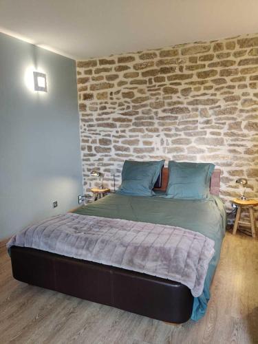 a bedroom with a large bed with a brick wall at Gîte d'olympe in Graffigny-Chemin