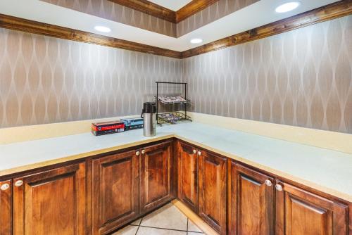 a kitchen with wooden cabinets and white counter tops at Super 8 by Wyndham Jackson MS Near the Fairgrounds in Jackson