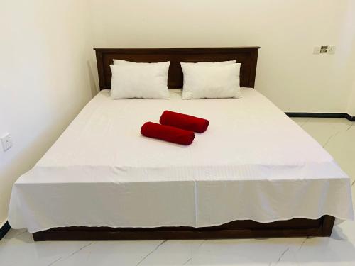 a red pillow sitting on a white bed at Wishwa Villa in Weligama