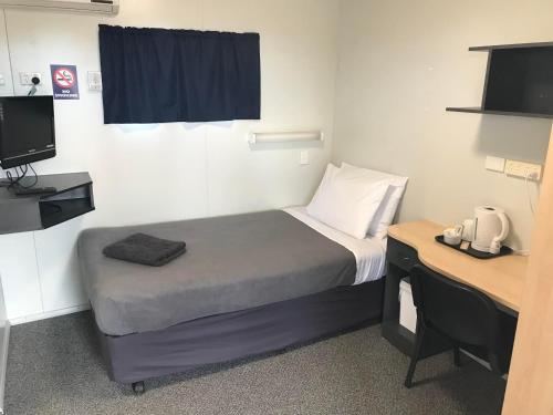 ein kleines Zimmer mit einem Bett, einem Schreibtisch und einem Fernseher in der Unterkunft Wheatsheaf Hotel in Price