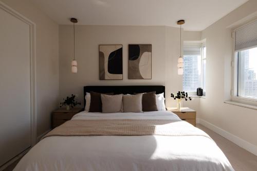 a bedroom with a large white bed with two windows at RARE Luxurious Apartment 1 Block From Time Square in New York