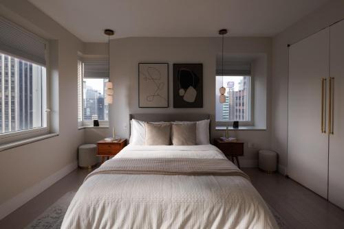 a bedroom with a large bed and two windows at RARE Luxurious Apartment 1 Block From Time Square in New York