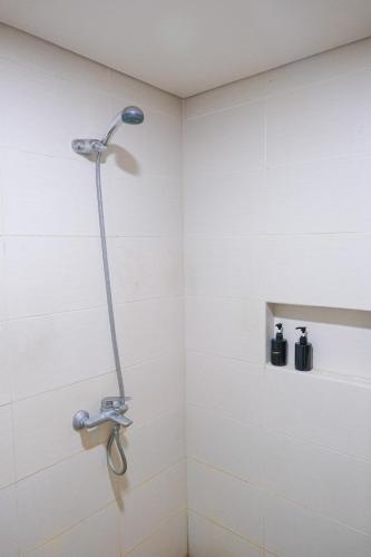 a shower in a bathroom with white tiles at Sampai Villa Vasana in Yogyakarta