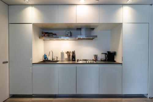 a kitchen with white cabinets and a sink at Stylish NYC Haven Steps to Broadway & Dining in New York