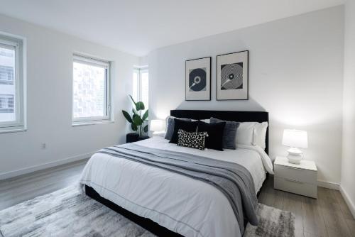 a white bedroom with a large bed and two windows at Stylish NYC Haven Steps to Broadway & Dining in New York