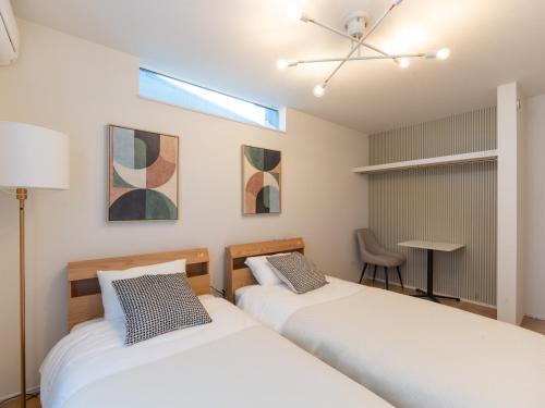 two twin beds in a bedroom with a window at 新築貸し切り宿 Karatsu House B in Karatsu