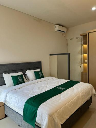 a bedroom with a large bed with green and white pillows at Sampai Villa Vasana in Yogyakarta