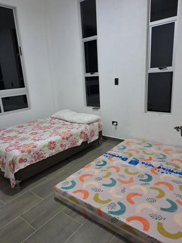 two beds sitting in a room with windows at Finca Villeta in Villeta