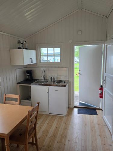 a kitchen with white cabinets and a table and a door at Edsken Camping in Hofors
