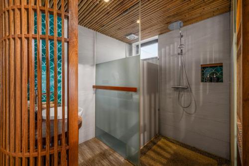 a bathroom with a shower with a glass door at LUK Inn Hotel - An Thuong, Da Nang in Danang