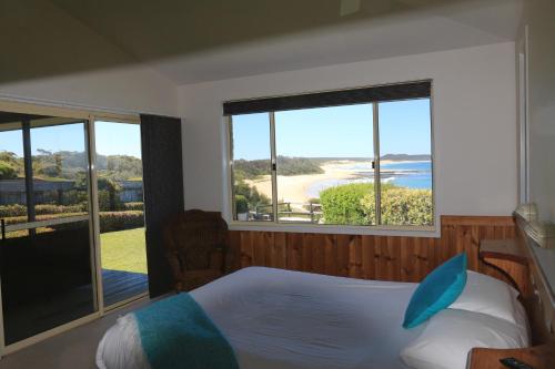 a bedroom with a bed and a view of a beach at Bunkys By The Sea Holiday House in Berrara