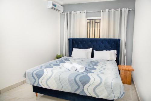 a bedroom with a blue bed with two towels on it at The View Apartments Salagi in Brusubi