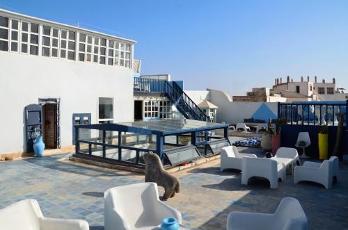 a patio with white chairs and a table on a building at La Maison des Artistes in Essaouira