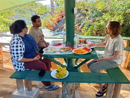 a group of people sitting around a table eating food at Sinharaja-Forest Cave Camp in Ullinduwawa