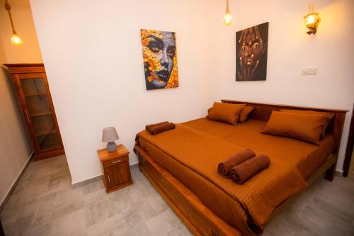 a bedroom with a bed with orange sheets and paintings at The Lux Villa in Habaraduwa Central
