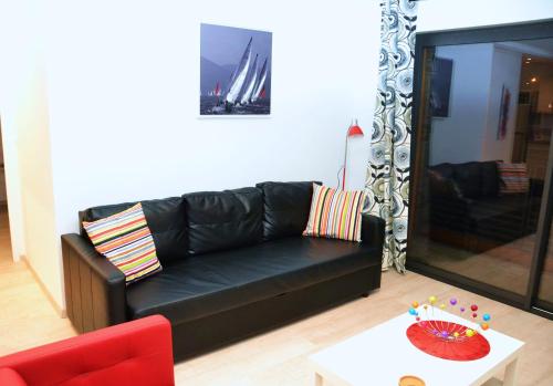 a black leather couch in a living room with a table at Appartement Alouette France in Pessac