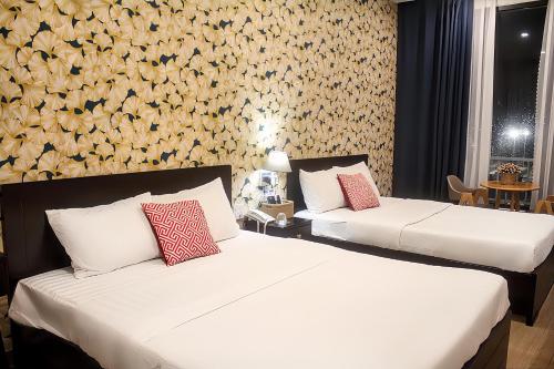 two beds in a hotel room with flowers on the wall at Khách Sạn Nhơn Lý LYS HOTEL in Quy Nhon