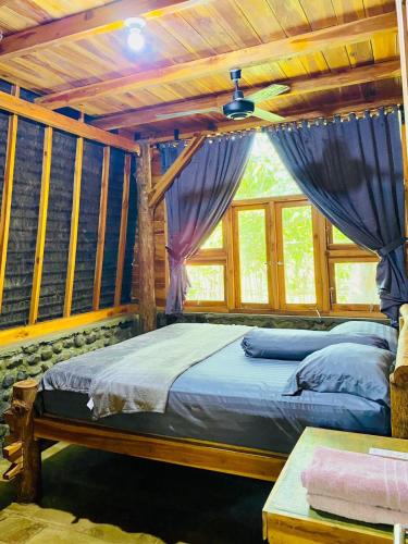 a bedroom with a bed in a room with windows at Triple J Villa in Sekongkang Bawa