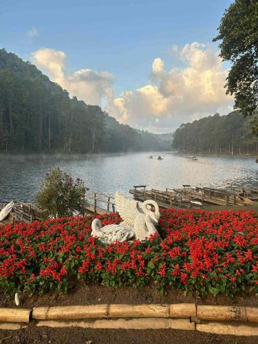 a statue of a swan sitting in a bed of flowers at โบว์ โฮมสเตย์ปางอุ๋ง in Ban Huai Makhuea Som
