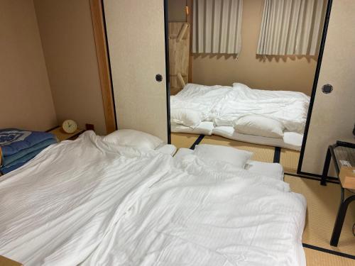 an unmade bed in a room with a mirror at PhaseSpace in Sekimachi