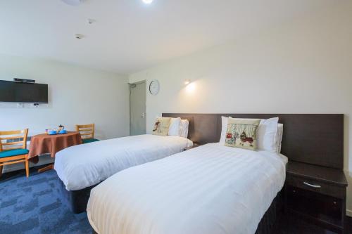 a hotel room with two beds and a table at Greenlane Motel in Auckland