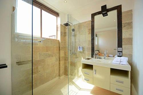 a bathroom with a shower and a sink and a mirror at Flora Apartment Bali in Seminyak