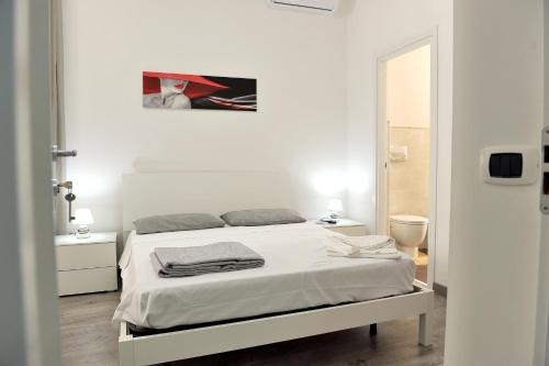 a white bedroom with a bed and a mirror at B&B Rosy in Paola