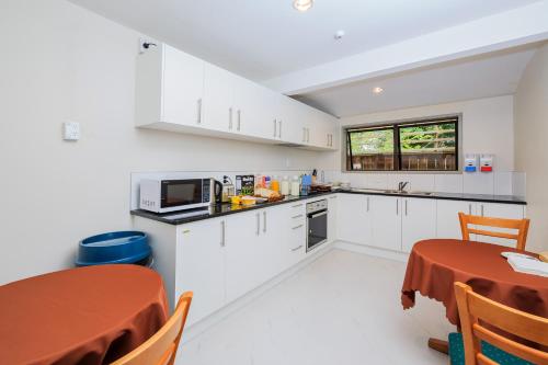 a kitchen with white cabinets and a table and a window at Greenlane Motel in Auckland