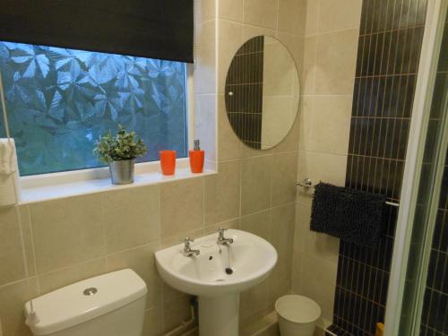 een badkamer met een wastafel, een toilet en een raam bij Lakeside View, Perton Village in Wolverhampton