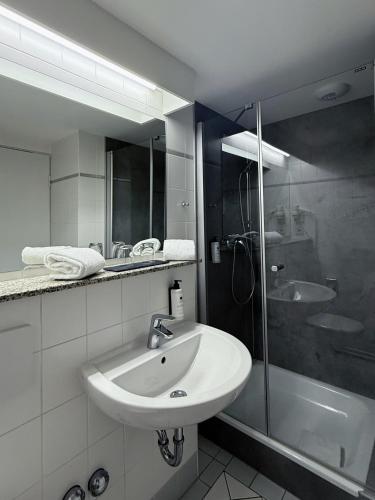 a white bathroom with a sink and a shower at RÜGEN-HOTEL mit Ostseeblick in Sassnitz