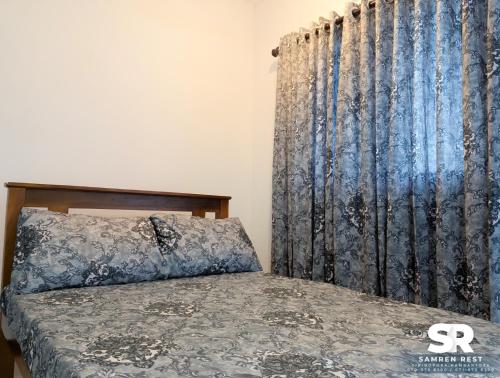 a bedroom with a bed and a blue curtain at Samren Rest in Hambantota