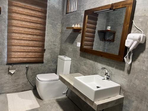 a bathroom with a sink and a toilet and a mirror at Saffron Lake Yala in Tissamaharama