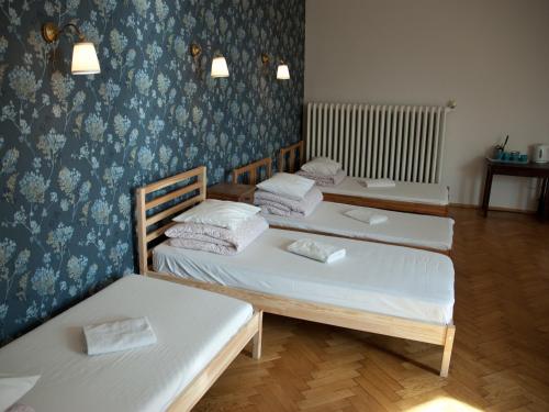 three beds in a room with blue wallpaper at Trzy Kafki Private Rooms in Kraków