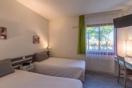 a hotel room with two beds and a window at Aliotel in Cazères-sur-lʼAdour