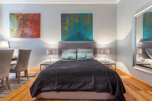 1 Schlafzimmer mit einem Bett mit 2 Stühlen und 2 Gemälden in der Unterkunft GreatStay Apartment - Paul Robeson Str. in Berlin