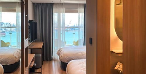 a hotel room with two beds and a balcony at Busan CONNECT Ocean Hotel in Busan