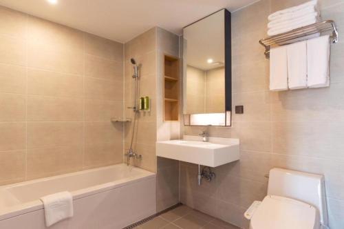 a bathroom with a sink and a tub and a toilet at Busan CONNECT Ocean Hotel in Busan