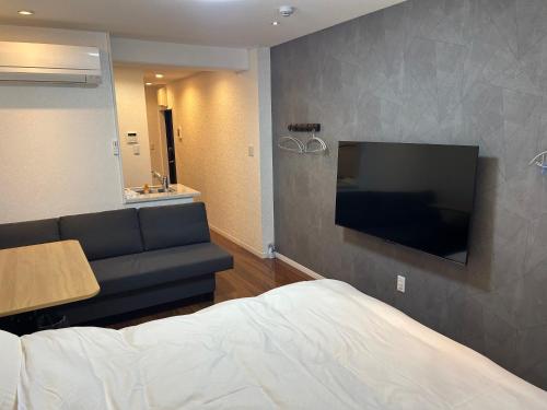 a bedroom with a couch and a flat screen tv at Eko House in 横浜石川町駅 in Yokohama