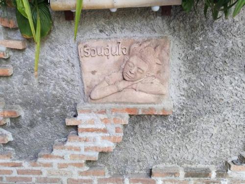 a stone relief of a child on the side of a building at Une Jai Place เรือนอุ่นใจ in Phimai