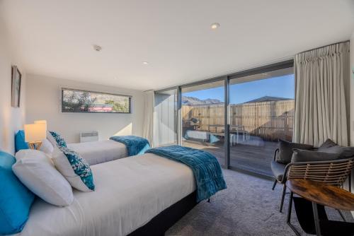 a bedroom with a large bed and a large window at Aspiring View Apartments - Modern & Stylish 3-BRM, 3-BTH - 2 Min Walk to Lake & Town in Wanaka