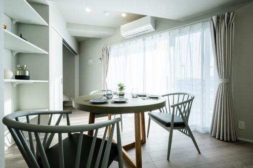 a dining room with a table and chairs and a window at Zee Haven nagasakiekimae - ZEE HAVEN長崎駅前 in Nagasaki