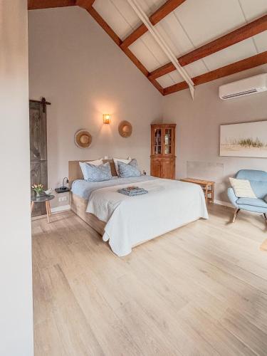 a bedroom with a white bed and a chair at Sea You Soon in Callantsoog