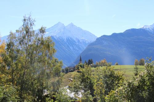 a church in a field with mountains in the background at Appartamenti Le Bistrot in Saint Nicolas