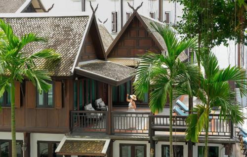 a house with a balcony with palm trees at Buri Sriping Riverside Resort & Spa in Chiang Mai