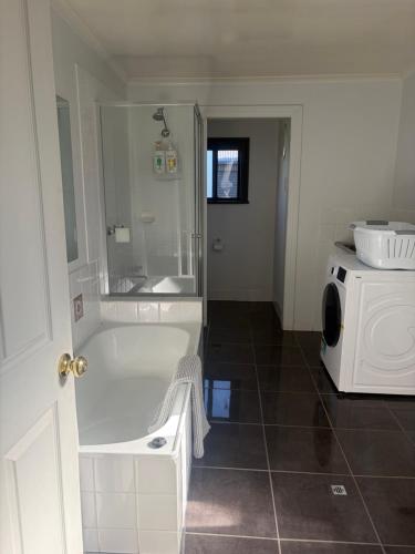 a white bathroom with a tub and a microwave at Albury Central Hideaway at Somerby in Albury