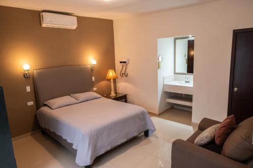 a bedroom with a bed and a couch and a mirror at Casa Rosales in Los Mochis