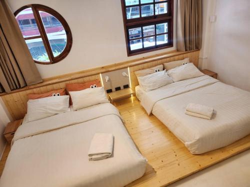 two beds in a room with two windows at Jellyfish Hostel in Jomtien Beach