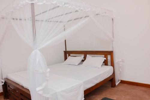 a bedroom with a bed with a canopy at Anula Villa in Ahangama